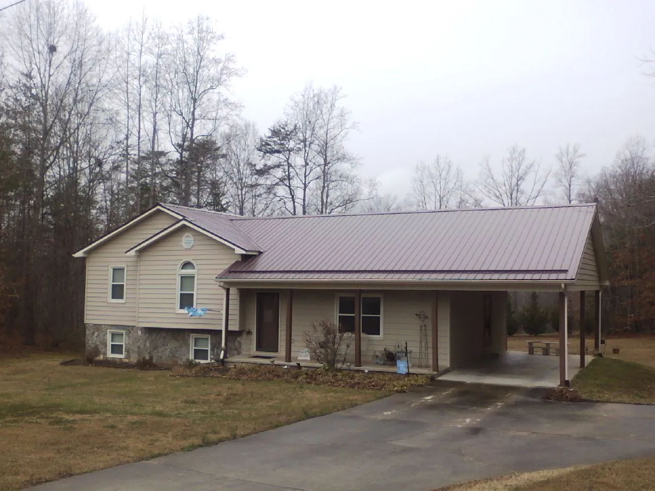 Burgundy metal roof on a tan split level home with an attached carport in Cathedral City