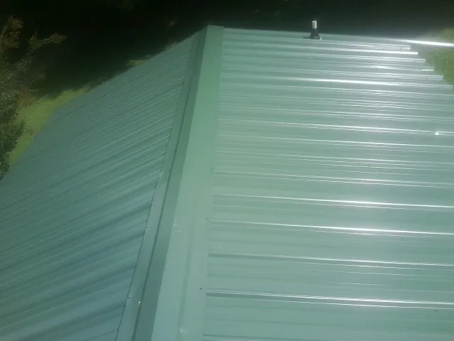 New green metal panels meeting at the ridge of a roof — Flat Roof Repair work by our crew in Cathedral City