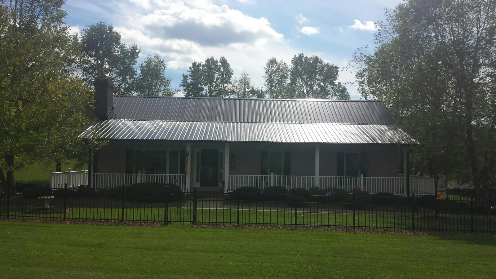 Gray metal roof on a brick ranch with a full width front porch — Gutter Guard Installation work by our crew in Cathedral City