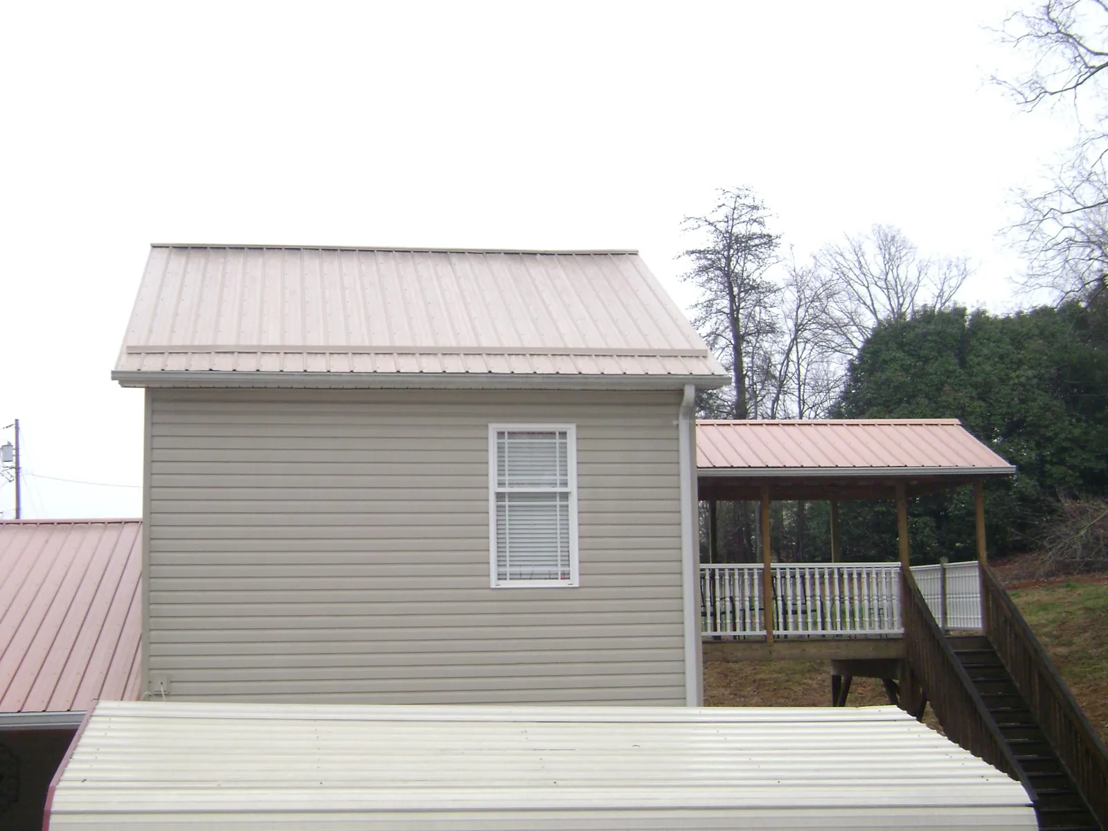 Tan metal roofs on a two story addition and attached porch, from a Roof Replacement job in Cathedral City