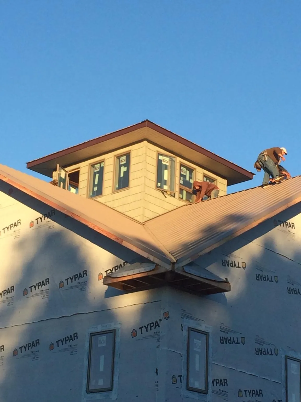 Roofers working around a rooftop cupola on a new metal roof at sunset — Roof Waterproofing in Cathedral City by Roofing Brothers